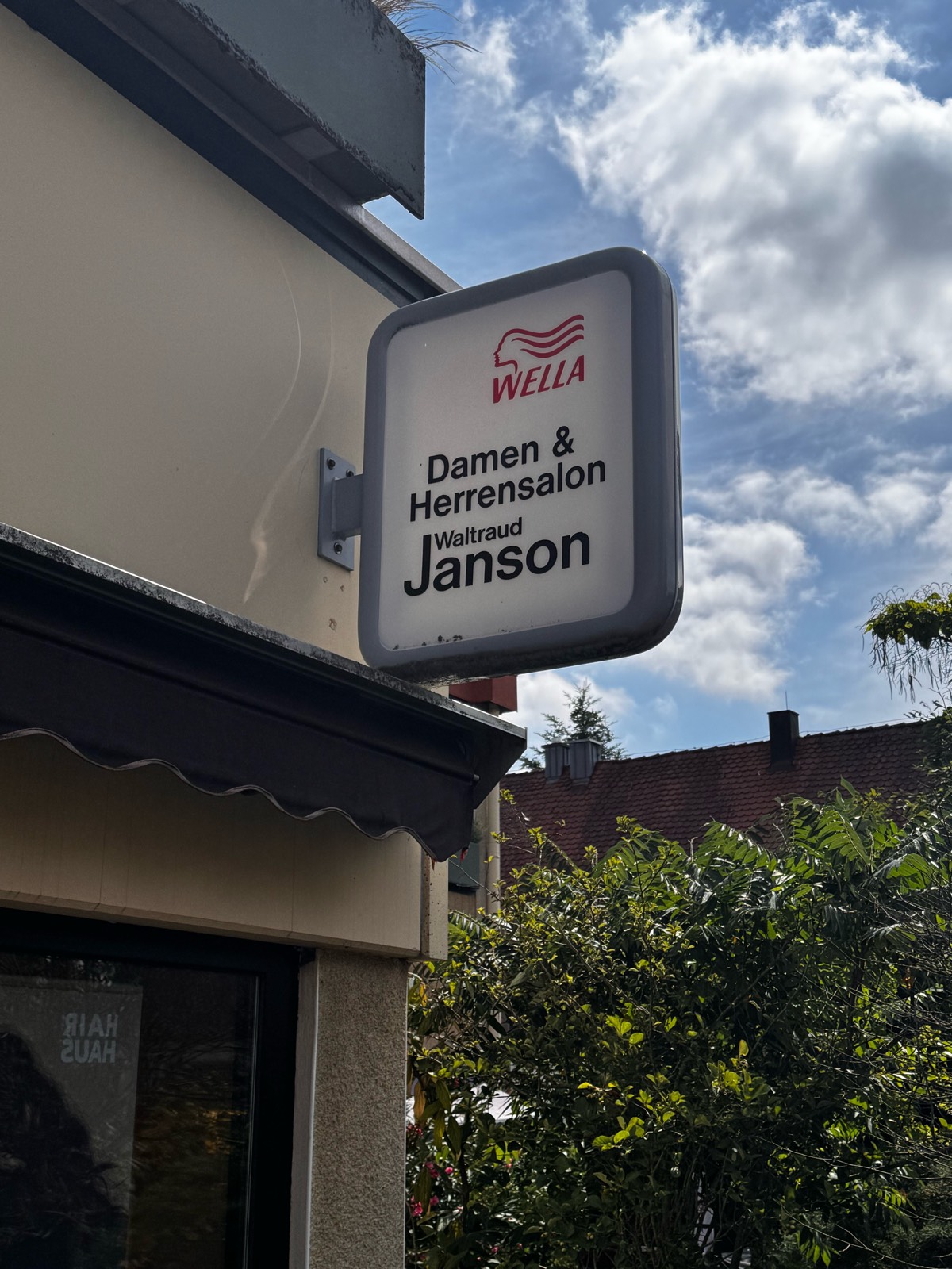 Das Salonschild „Damen & Herrensalon Waltraud Janson" an der Fassade Am Tennenbach 2